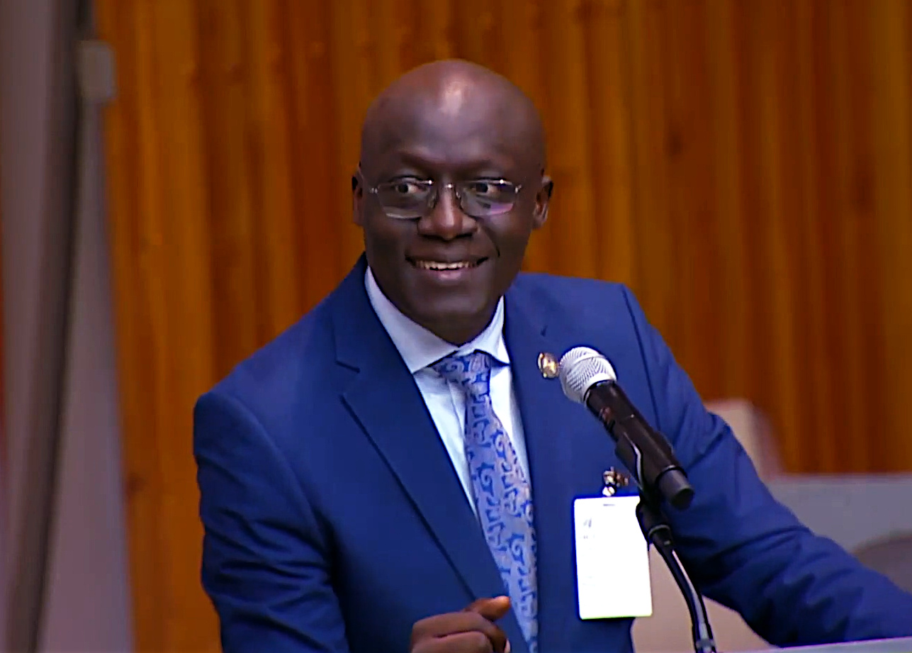 A man in a suit speaking behind a lectern