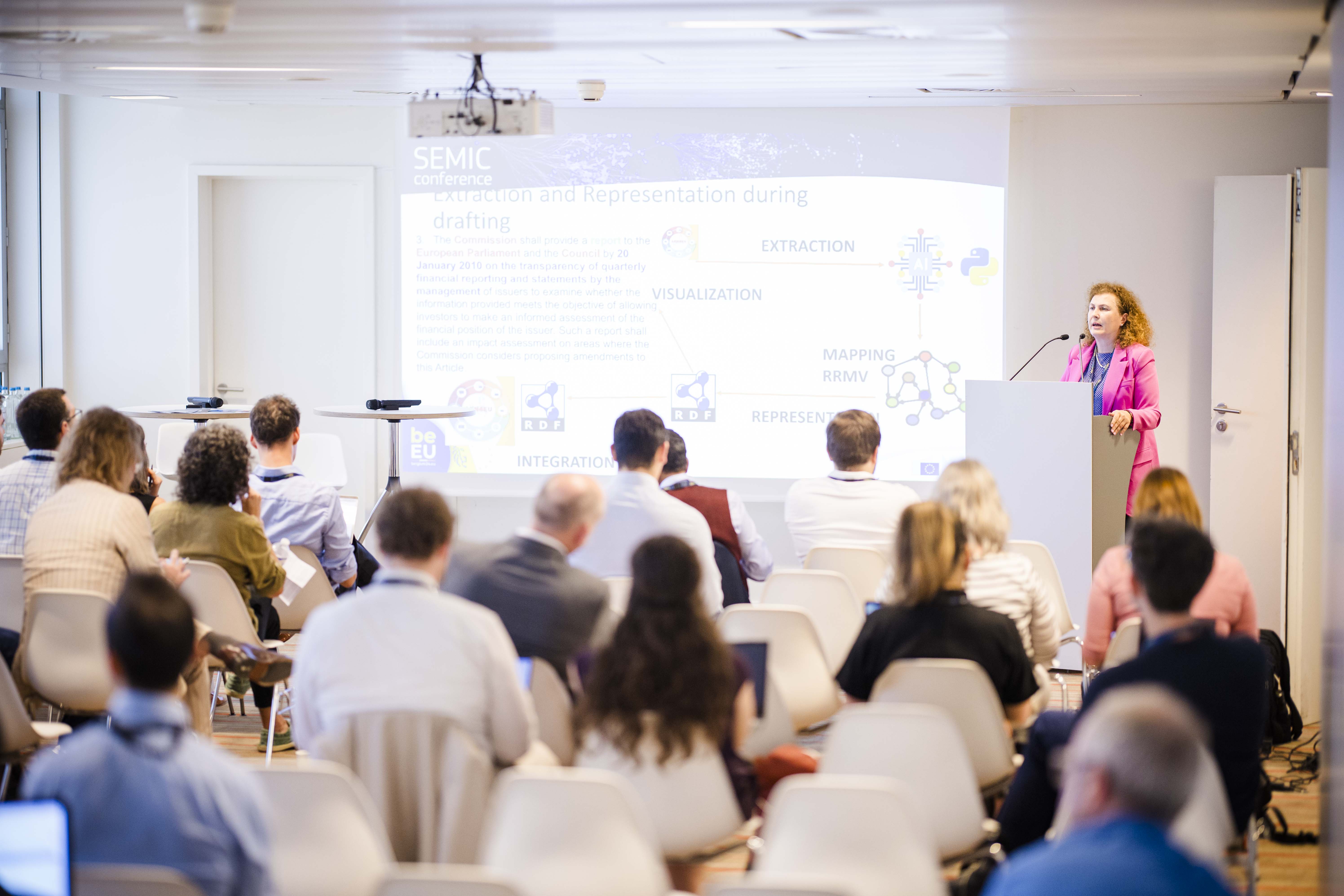 A woman in pink delivering a presentation