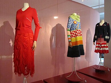 An exhibition of three manequins wearing dresses in the Fashion Museum of Antwerp