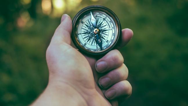 A hand holding a compass