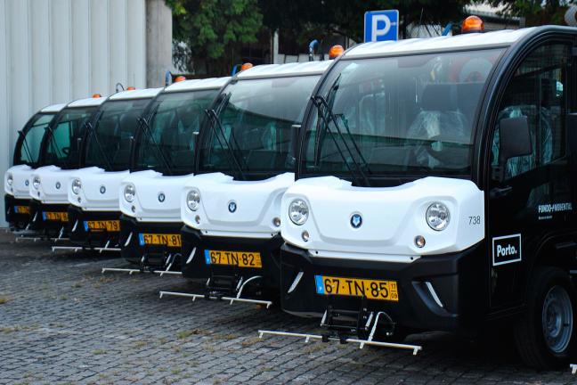 The image shows a row of parked electric street sweper cars, from the city of Porto