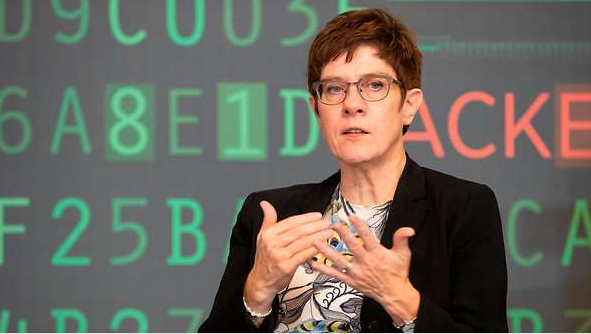 The image shows defence minister Annegret Kramp-Karrenbauer against a background of digital numbers and characters. 
