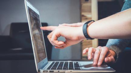 Fingers pointing to a computer screen