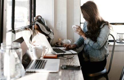 A woman using computer and drinking coffee